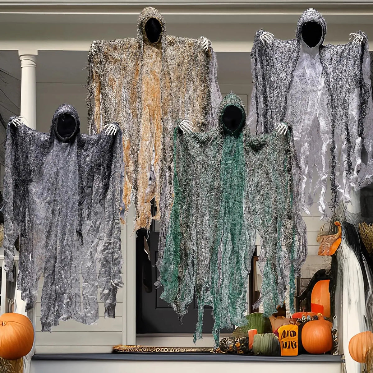 Four hanging ghosts on a front porch with pumpkins for Halloween