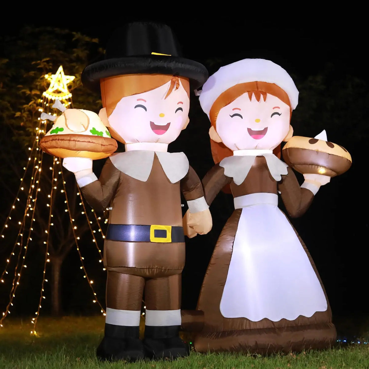 Light-up inflatable pilgrims glowing at night on a lawn