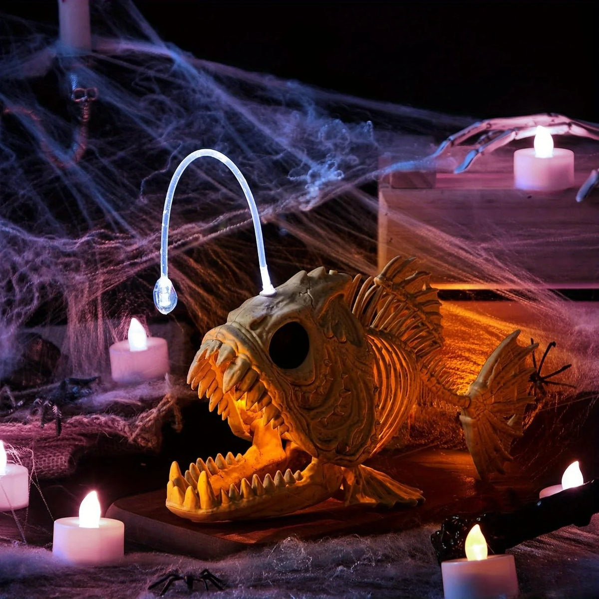 Glowing anglerfish skeleton in an indoor Halloween tabletop display with candles
