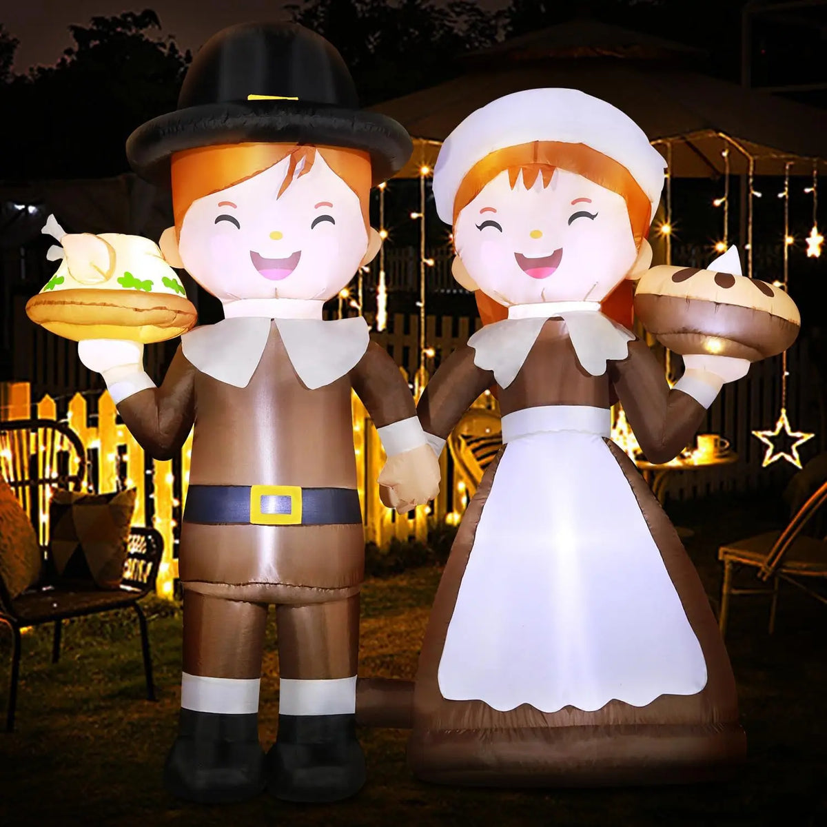 Glowing pilgrim boy and girl Thanksgiving yard decoration on a patio at night
